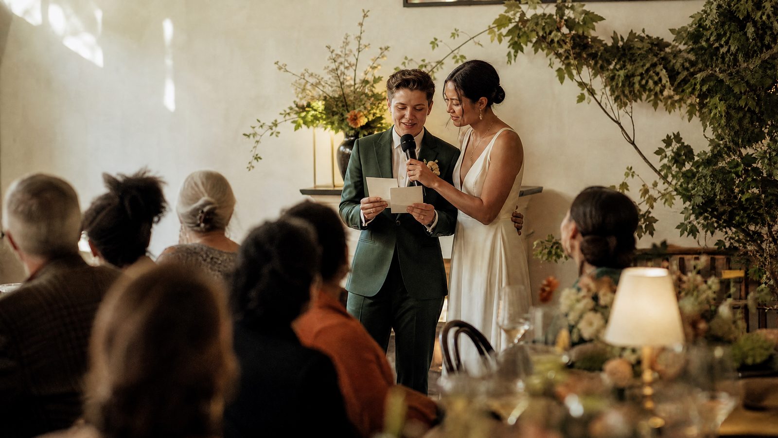 A newlywed couple sharing a microphone and thanking their wedding guests